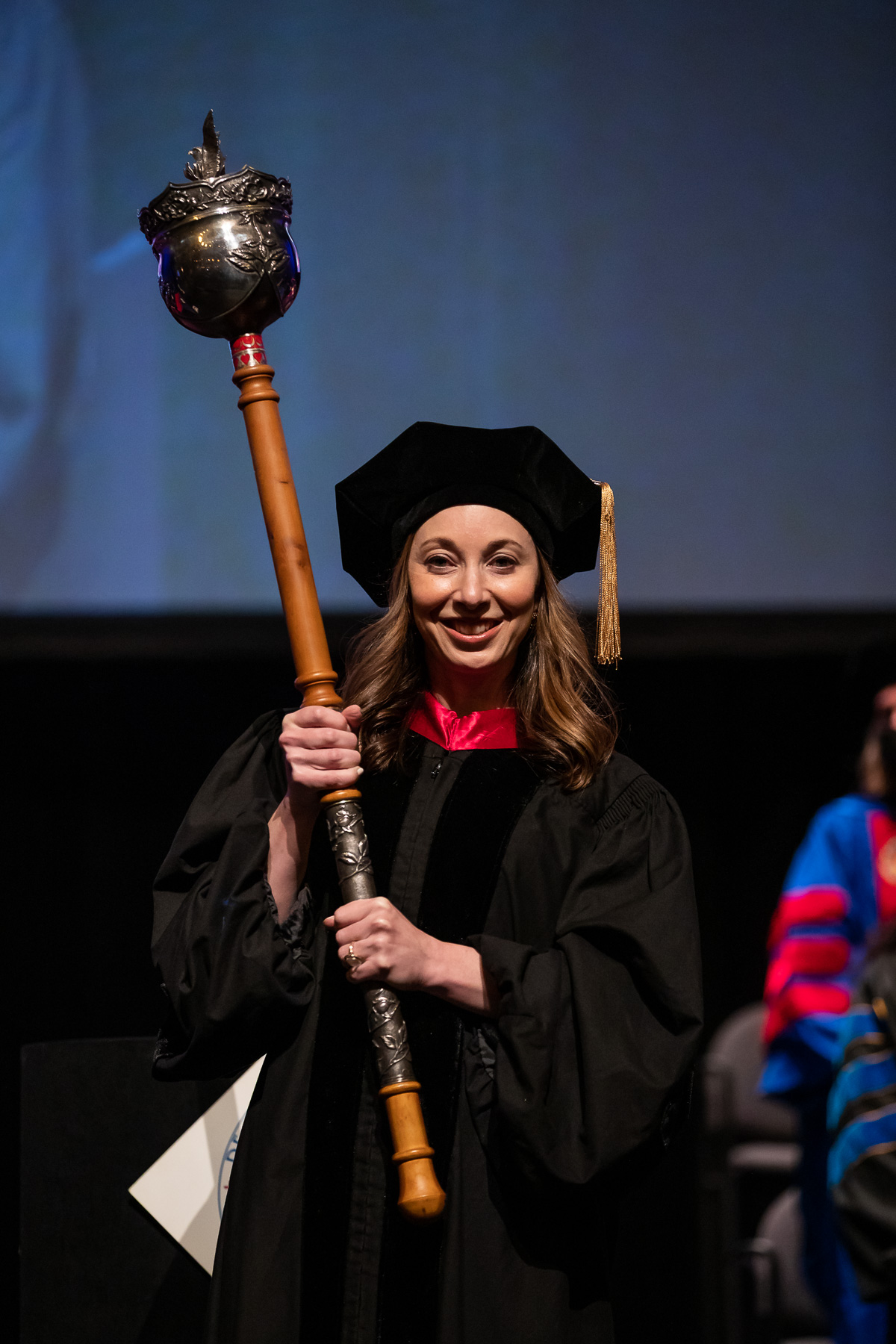 Wendy Epstein, professor of Law and associate dean of Research and Faculty Professional Development, carries the university mace during the procession.
